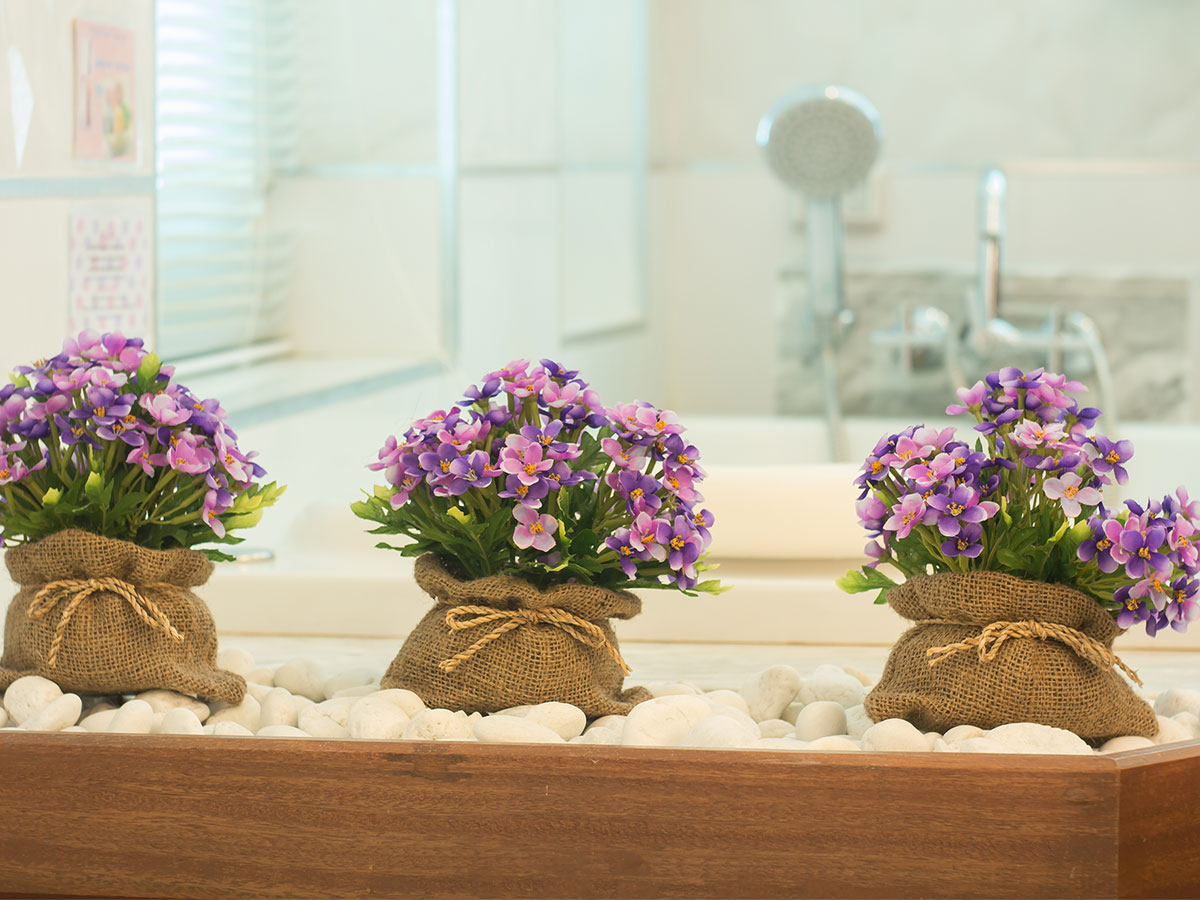 Bunches of flowers arranged in a wooden basket beset with white rocks in a bathroom